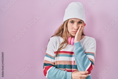 Young blonde woman standing over pink background thinking looking tired and bored with depression problems with crossed arms.