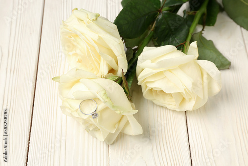 Roses with engagement ring on white wooden background  closeup