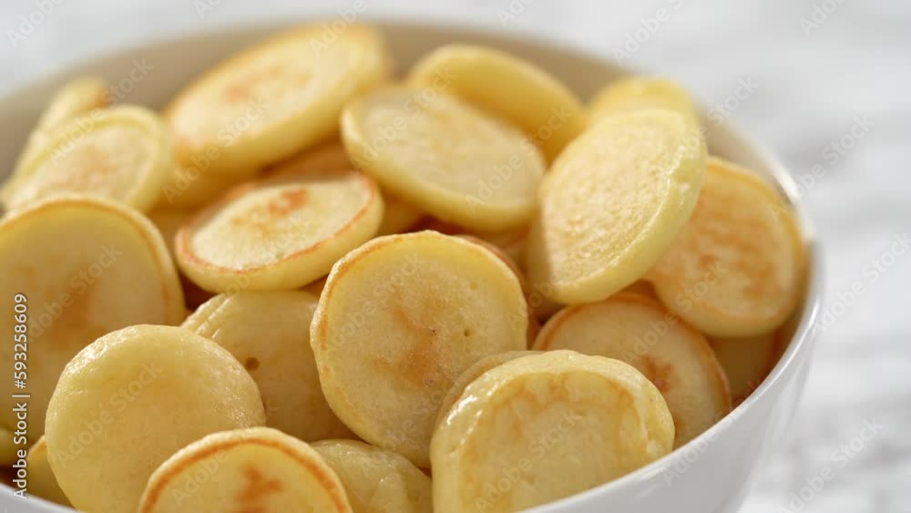 Step by step. Freshly made mini pancake cereal with fresh blueberries in a white bowl.