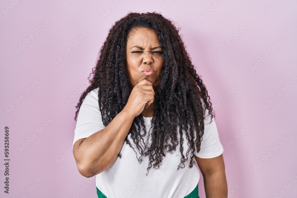 Plus size hispanic woman standing over pink background thinking worried about a question, concerned and nervous with hand on chin