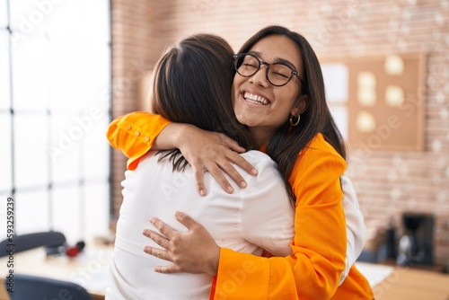 Two women business workers hugging each other at office photo