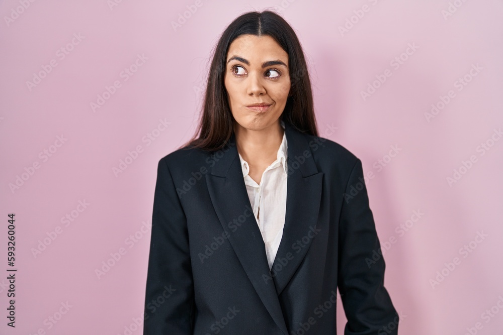 Young brunette woman wearing business style over pink background smiling looking to the side and staring away thinking. Young brunette woman wearing business style over pink background smiling looking to the side and staring away thinking.