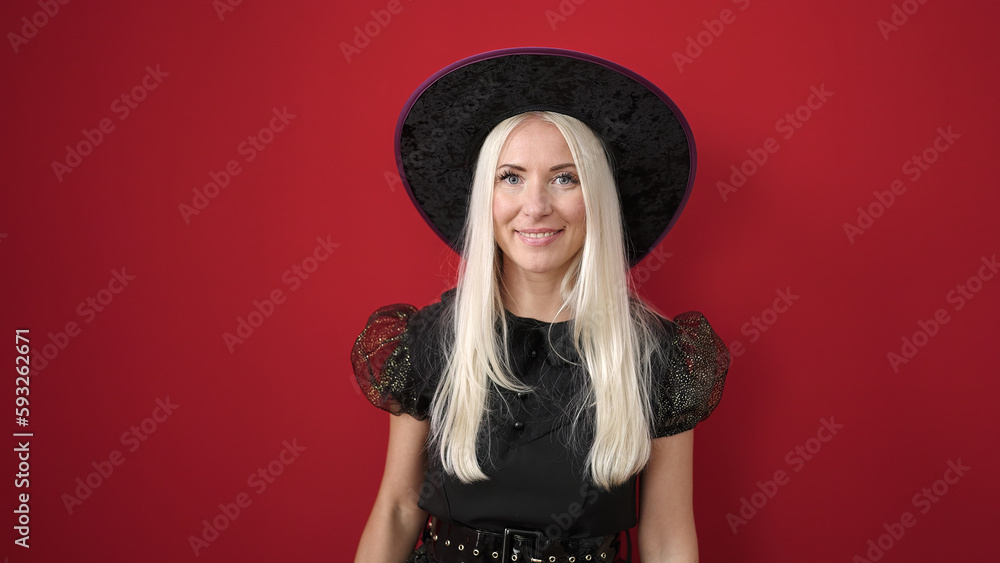 Young blonde woman wearing witch costume smiling confident over isolated red background Young blonde woman wearing witch costume smiling confident over isolated red background