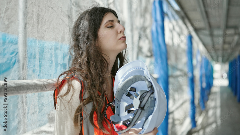 Young beautiful hispanic woman builder stressed suffering for hot weather at street Young beautiful hispanic woman builder stressed suffering for hot weather at street