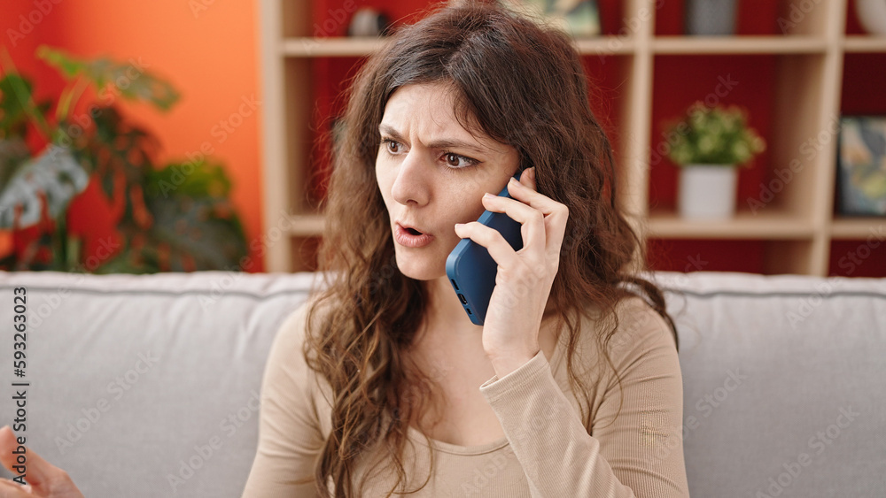 Young beautiful hispanic woman talking on smartphone upset at home Young beautiful hispanic woman talking on smartphone upset at home