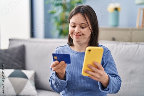 Young woman with down syndrome using smartphone and credit card sitting on sofa at home © Krakenimages.com