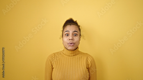 Young african american woman standing with surprise expression over isolated yellow background