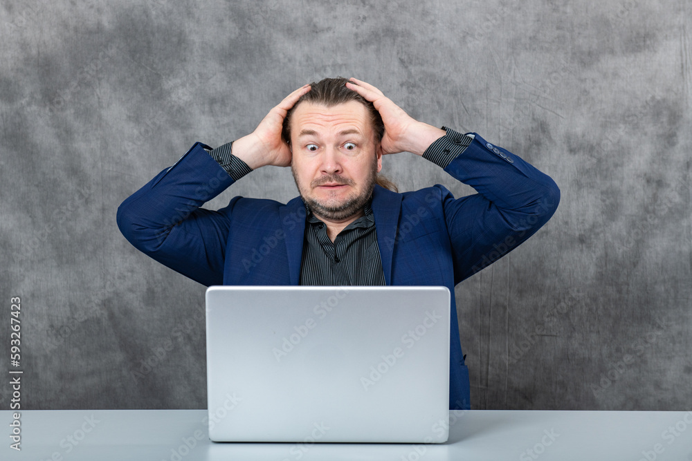 a surprised man in a jacket at a laptop works a surprised man in a jacket at a laptop works