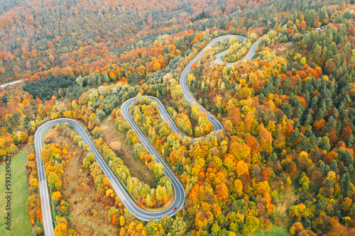 Aerial view of mountain road in forest at sunset in autumn