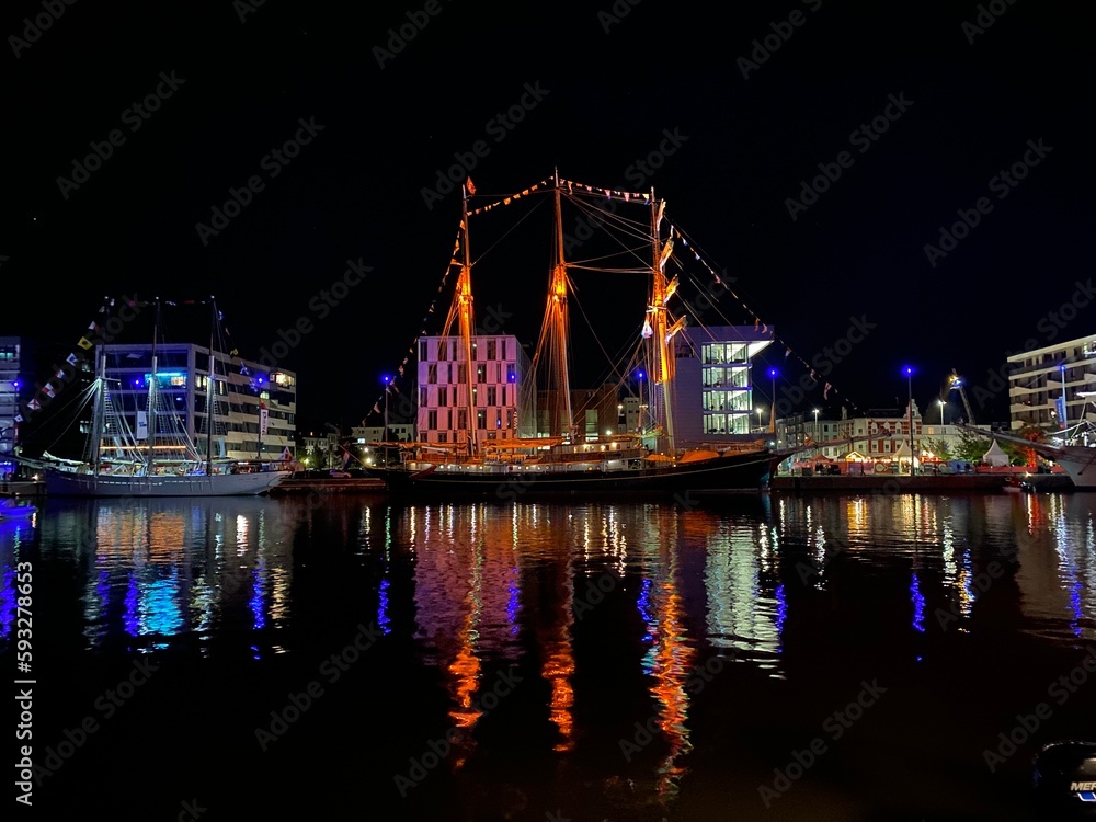 Obraz premium Nachtzauber am Bremerhaven: Das verträumte alte Boot und die reflektierenden Lichter