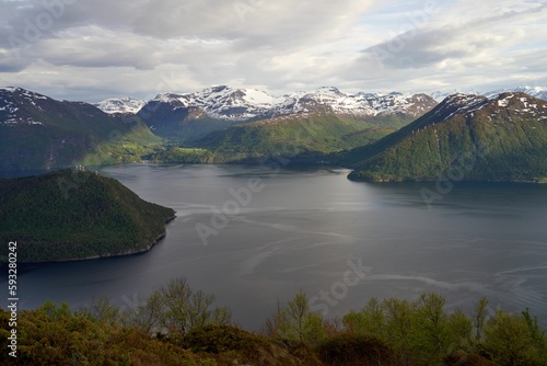 Aerial view of a fjord in Sjoholt, Norway surrounded by green mountains with snowy peaks in summer photo