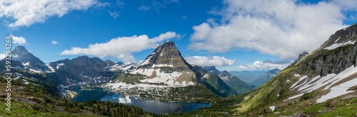 Scenic shot of a rocky hill with glacier and snow on its slopes near a small lake
