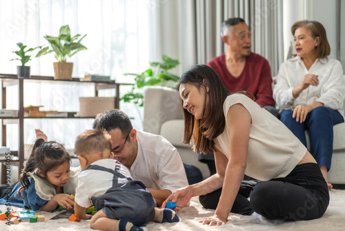 Portrait of enjoy happy love asian big family father and mother with little asian girl smiling activity learn and skill brain training play with toy build wooden blocks board education game at home