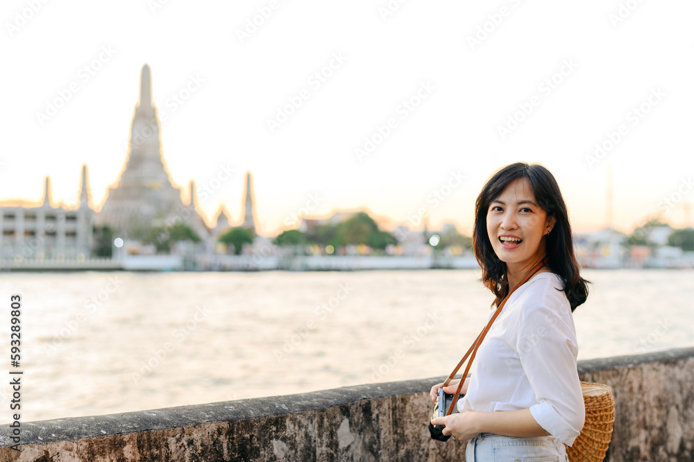 Portrait young beautiful asian woman smiling while travel at Wat Arun sunset view point, Bangkok, Thailand.