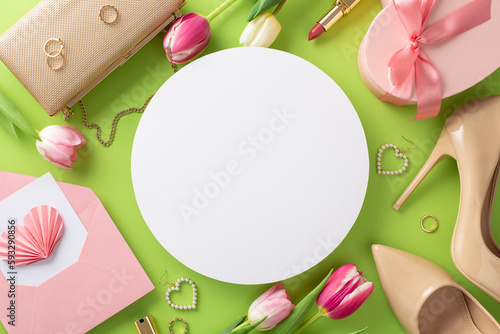 Joyful Mother's Day concept. Flat lay top view of high-heels, handbag, present box, tulips, lipstick, makeup brush, and earrings on pastel green background with a blank circle for text or advert