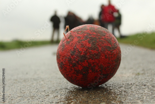 Boßelkugel rot mit Menschen im Hintergrund