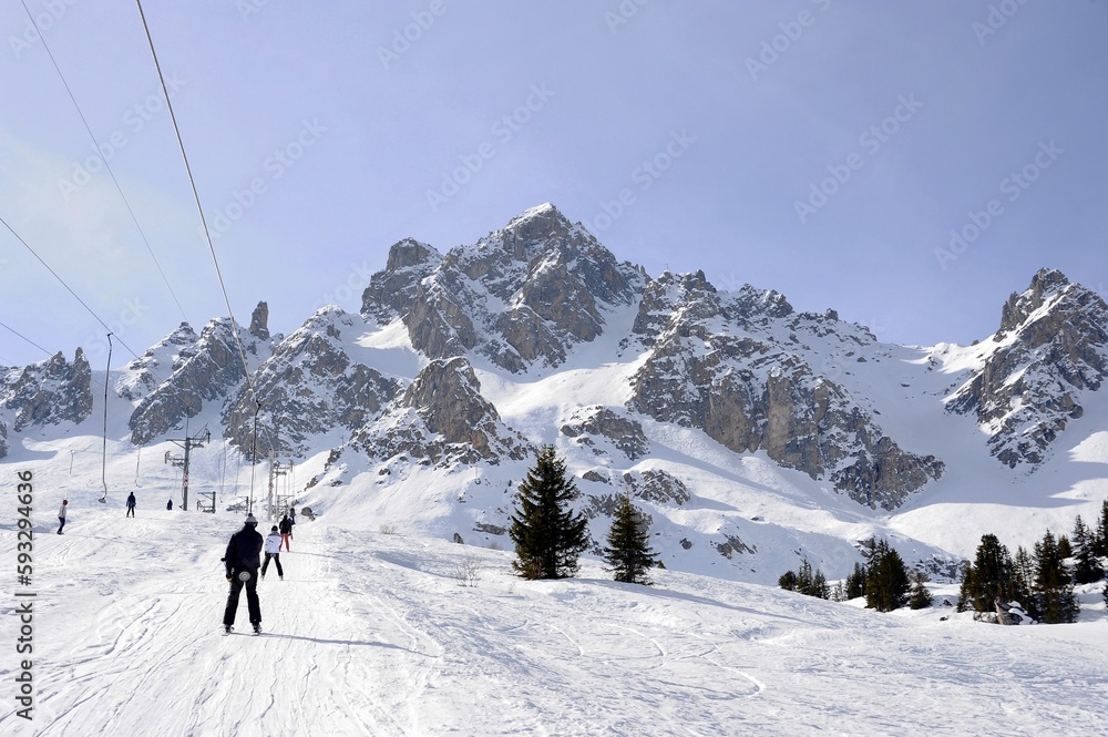 People on drag lift going up at French alps.