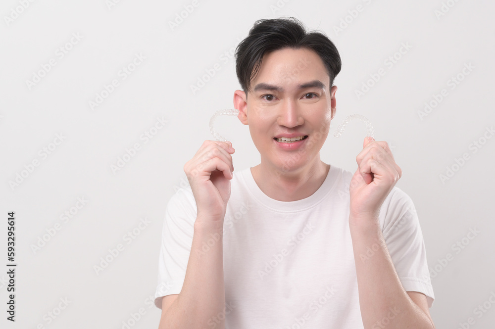 Young smiling man holding invisalign braces over white background studio, dental healthcare and Orthodontic concept... Young smiling man holding invisalign braces over white background studio, dental healthcare and Orthodontic concept...
