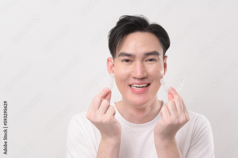 Young smiling man holding invisalign braces over white background studio, dental healthcare and Orthodontic concept... Young smiling man holding invisalign braces over white background studio, dental healthcare and Orthodontic concept...