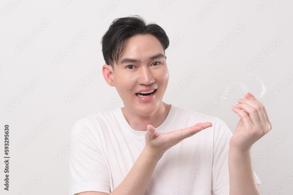 Young smiling man holding invisalign braces over white background studio, dental healthcare and Orthodontic concept... Young smiling man holding invisalign braces over white background studio, dental healthcare and Orthodontic concept...