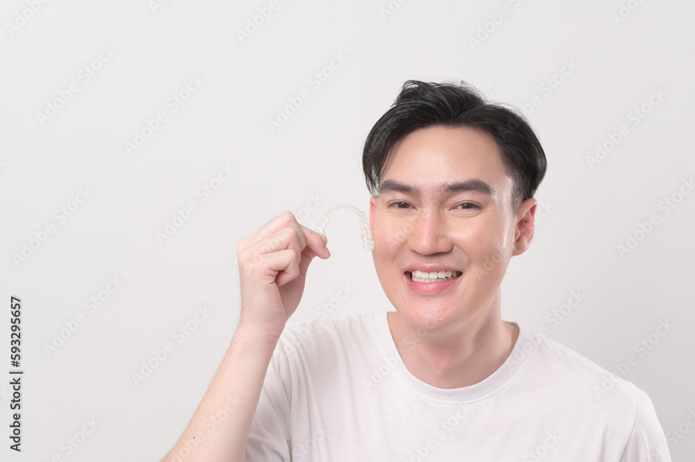 Young smiling man holding invisalign braces over white background studio, dental healthcare and Orthodontic concept... Young smiling man holding invisalign braces over white background studio, dental healthcare and Orthodontic concept...