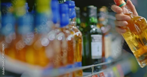 man taking whiskey bottle from shelf in supermarket, closeup view in liquor store, 4K, Prores
