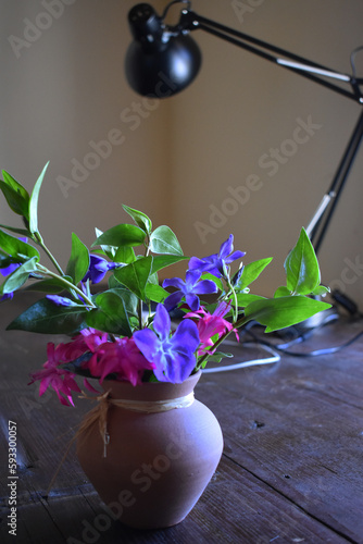 jarrón con flores sobre una mesa con una lampara