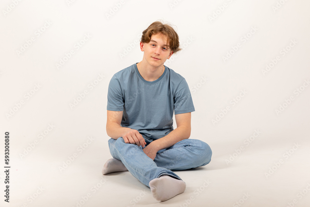 Lifestyle, fashion,full length view of young man in jeans and white t-shirt sitting cube on white background Lifestyle, fashion,full length view of young man in jeans and white t-shirt sitting cube on white background