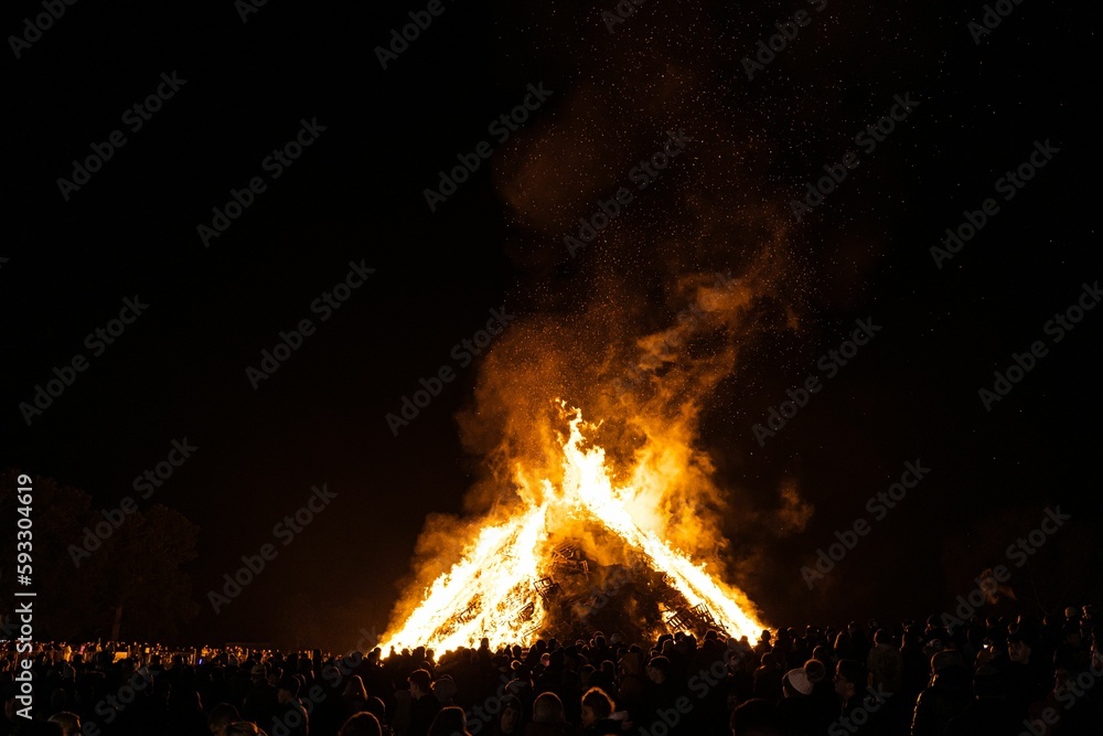 Stunning view of a crowd watching a big bonfire burning against a dark sky at night