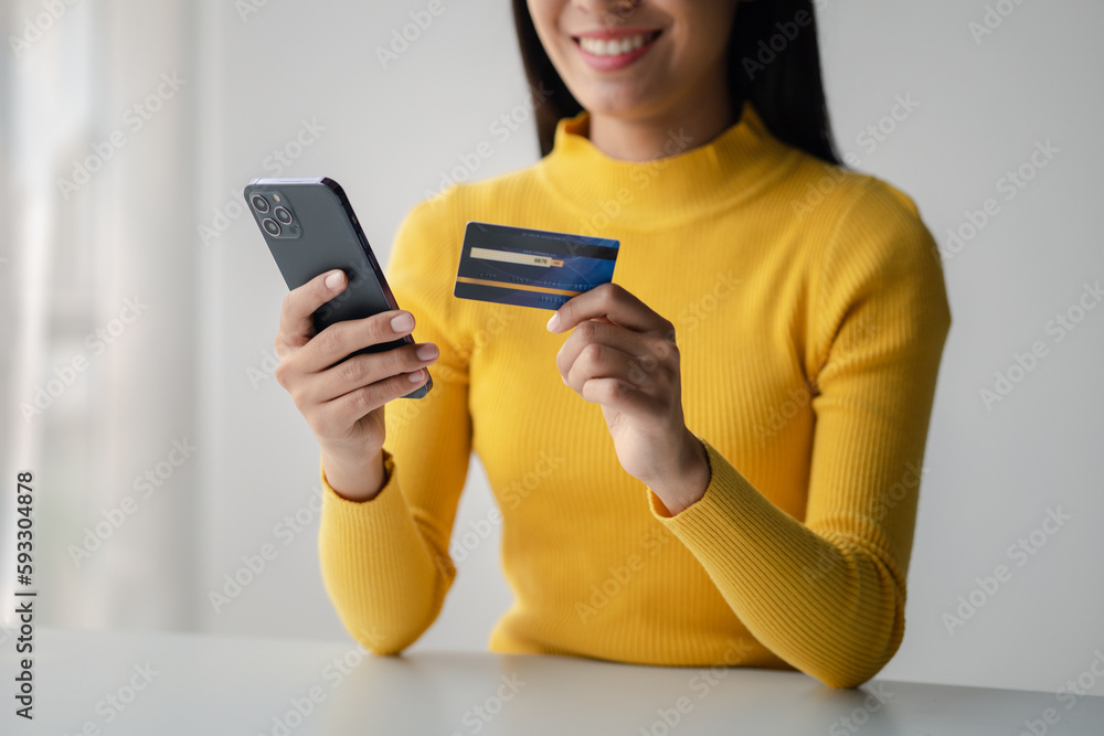 Beautiful woman holding a credit card, she uses a credit card to pay for goods and services online, the concept of using a credit card for online shopping, ordering goods and services on the website. Beautiful woman holding a credit card, she uses a credit card to pay for goods and services online, the concept of using a credit card for online shopping, ordering goods and services on the website.
