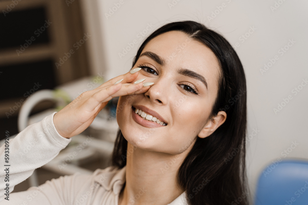 Girl touches her nose and smiles after septoplasty nose surgery correction deformities of the nasal septum. Happy patient of ENT doctor. Girl touches her nose and smiles after septoplasty nose surgery correction deformities of the nasal septum. Happy patient of ENT doctor.