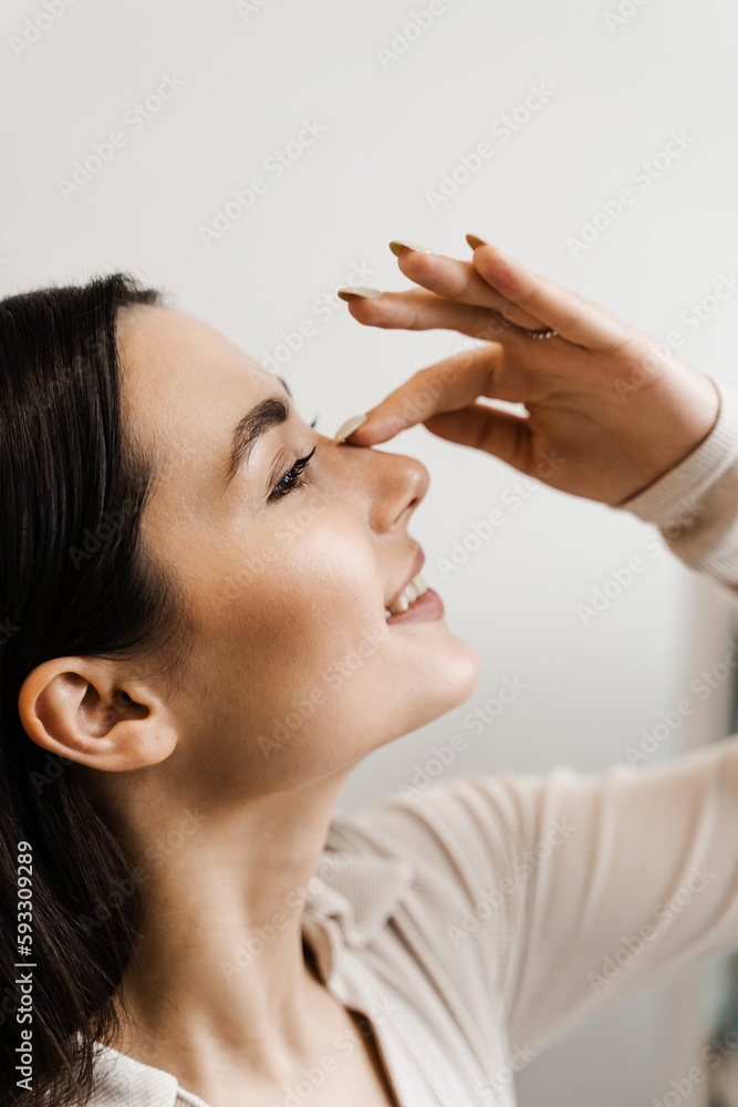 Girl touches her nose and smiles after rhinoplasty nose reshaping surgery for change appearance of the nose and improve breathing. Girl touches her nose and smiles after rhinoplasty nose reshaping surgery for change appearance of the nose and improve breathing.