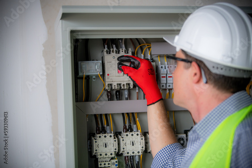 Side view of male technician examining fusebox with multimeter probe