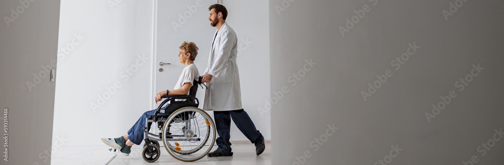 Professional male doctor carrying patient on wheelchair in medicine clinic hall. High quality photo Professional male doctor carrying patient on wheelchair in medicine clinic hall. High quality photo