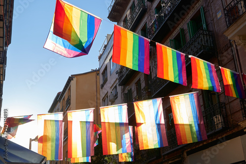 lgbt flags hanging over the street of the city center at sunset. Chueca, the epicenter of gay pride in Madrid photo