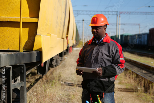 African american railway man with tablet computer at freight train terminal photo