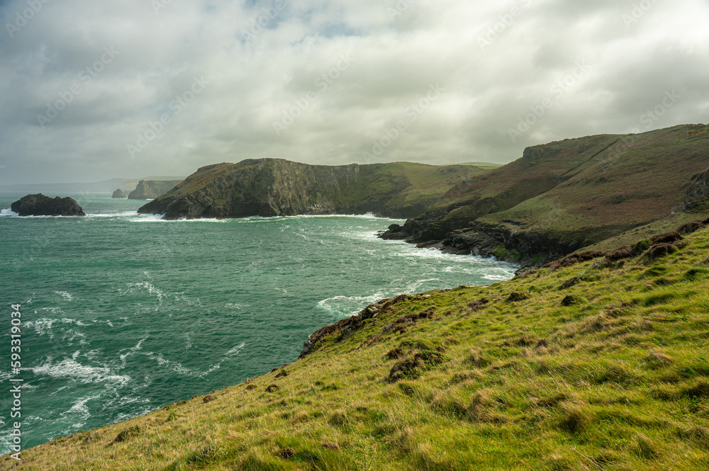 Küstenlandschaft in Cornwall – grüne Hügel und felsige Klippen bei Wolken und Sonne im Frühjahr