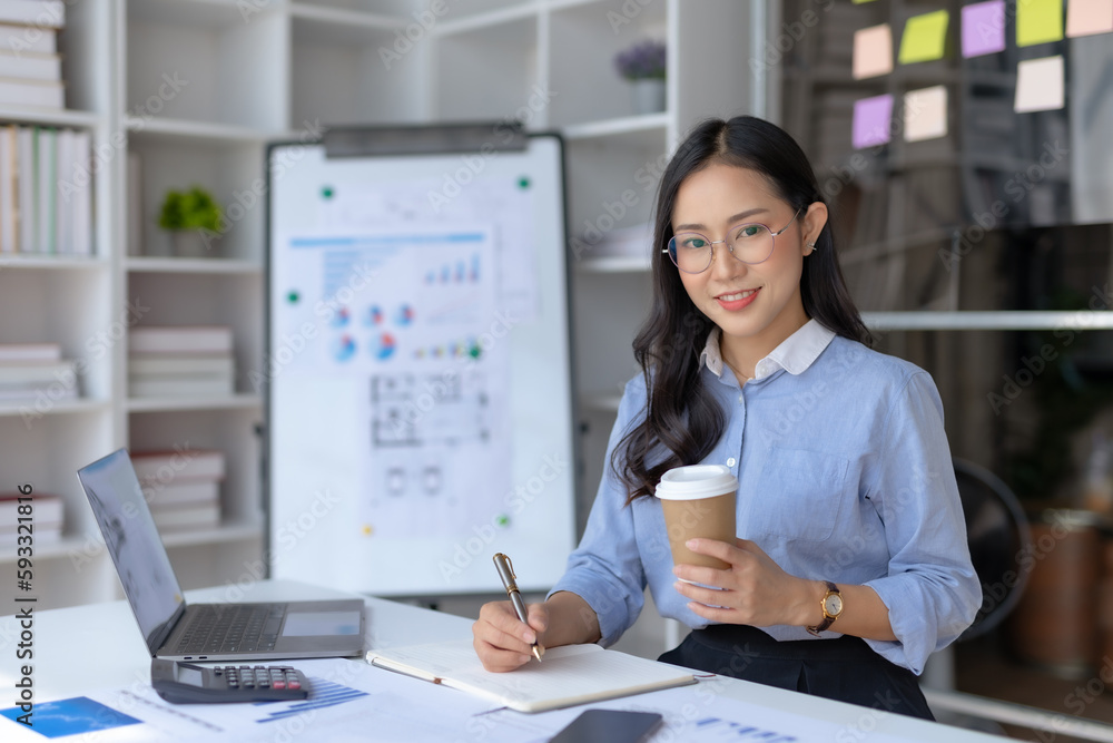 Happy young asian businesswoman sitting working at office and drinking coffee. Happy young asian businesswoman sitting working at office and drinking coffee.