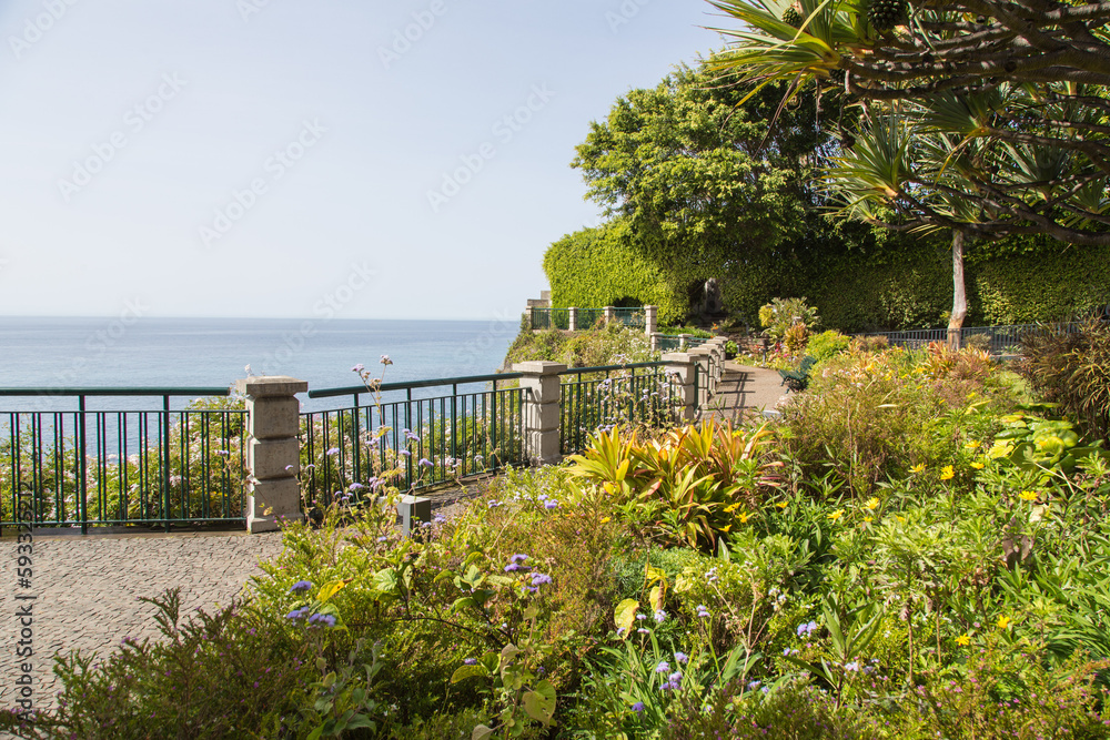 Nature, garden and landscape architecture in Madeira, Portugal-Garden and stone-cobbled terrace with lush green tropical and subtropical plants, benches and breathtaking view to the Atlantic ocean