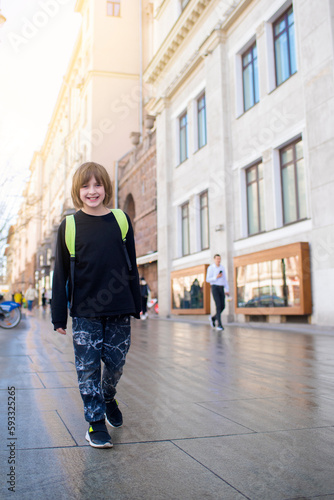 happy boy student in black clothes with a backpack walks around the city