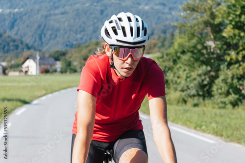 Caucasian girl cyclist with professional racing sports gear riding on an open road cycling route
