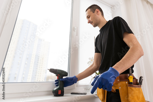 Master in gloves adjusting pvc windows with screwdriver closeup. Installation of plastic windows repair and maintenance concept