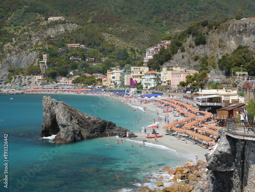 Bagni Eden beach with its orange and blue striped umbrellas at Monterosso al Mare seen from hiking trail. Cinque Terre, Italy
