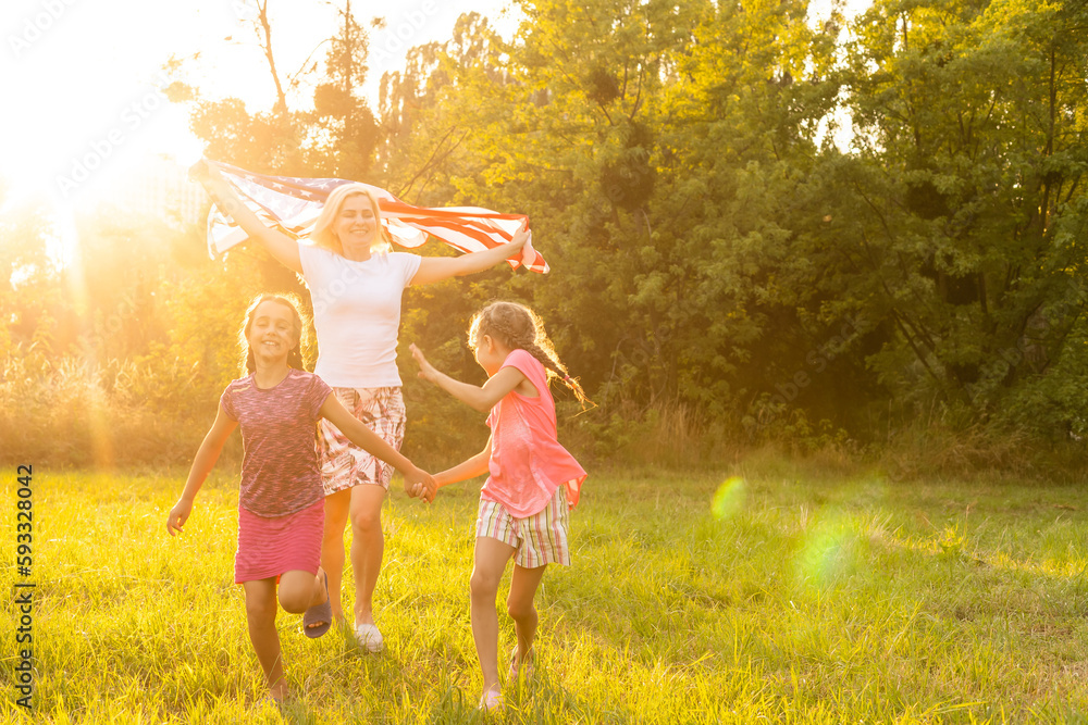 Fototapeta premium happy family with the flag of america USA at sunset outdoors