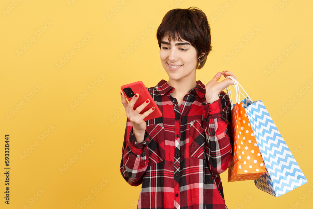 Androgynous person using a mobile while holding shopping bags Androgynous person using a mobile while holding shopping bags