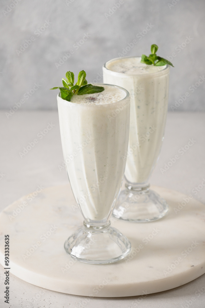 Indian Salty lassi with mint leaves and kala namak on white background. Vertical format. Traditional healthy freshness lassi made of yogurt, water, spices and ice.