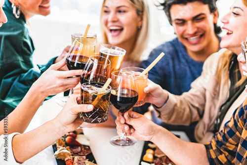 Obraz na płótnie Group of friends toasting fancy cocktails together sitting at bar restaurant tab