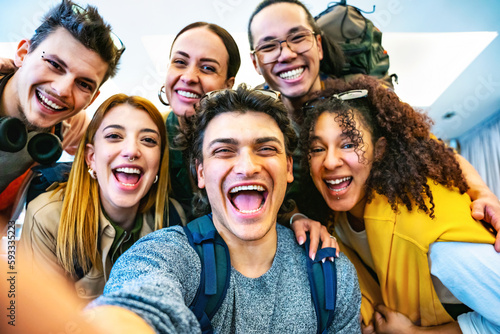 Happy multiracial friends travelers taking selfie shot at hostel reception- Young group of people having fun together looking at camera-Life Style concept with trendy students 
