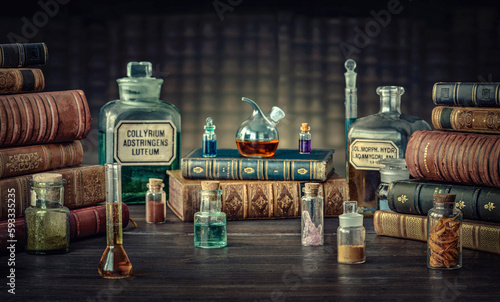 Glass bottles, old books on table of a scientist. Medicine, chemistry, pharmacy, apothecary, alchemy history background. Translation from labels-eyewash astringent, morphine hydrochloride and almonds.