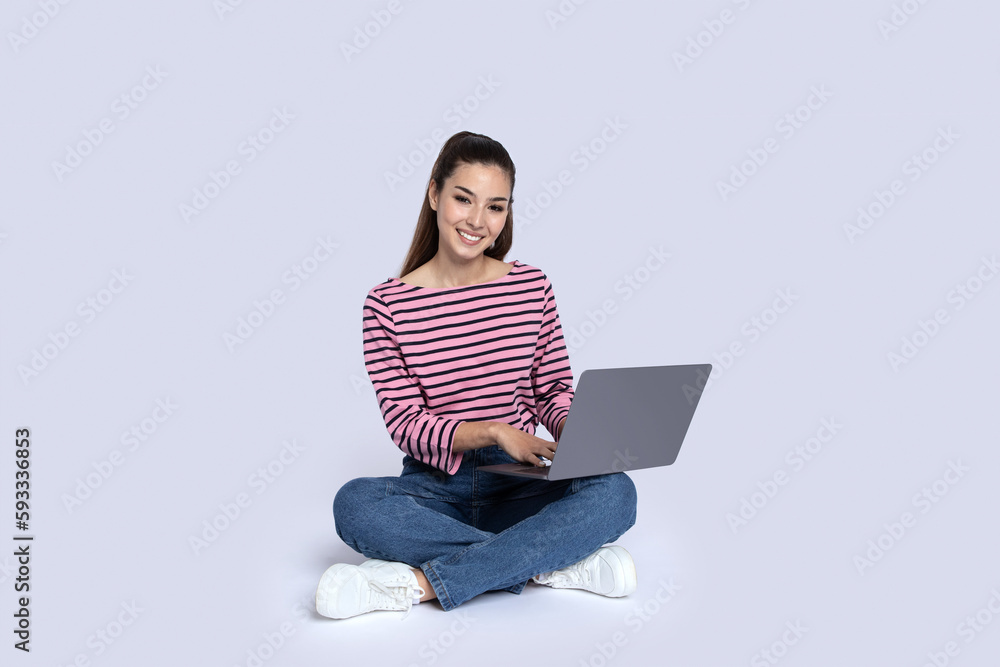 Cheerful young woman typing on laptop keyboard, sitting on floor Cheerful young woman typing on laptop keyboard, sitting on floor